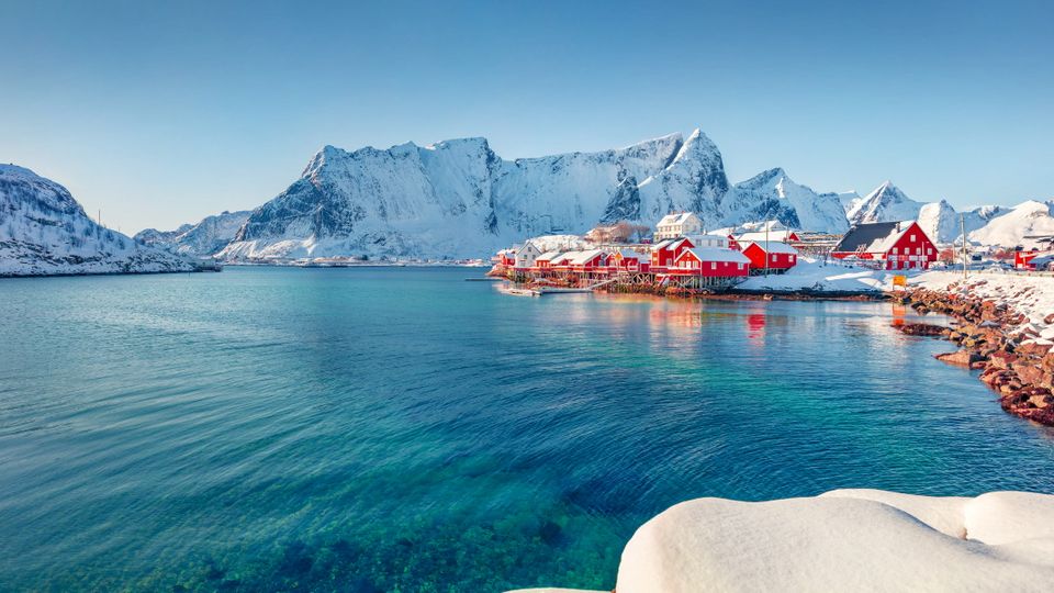 Rote Häuser am Ufer des Norwegischen Meeres. Sonnige Winteransicht des Fischerdorfes Sakrisoy