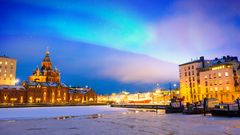 Nordlichter über dem gefrorenen Hafen in Katajanokka mit der orthodoxen Uspenski-Kathedrale in Helsinki